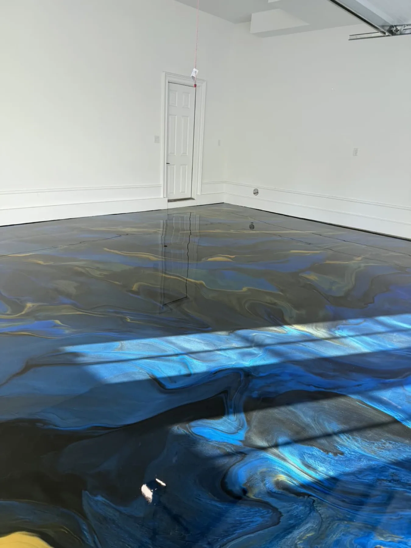 Blue and black metallic epoxy floor reflecting window light in Goldsboro, North Carolina